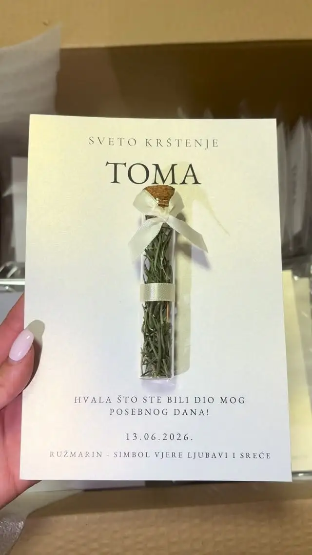 Kartica od perlastog papira s natpisom Sveto krštenje Toma i epruvetom ružmarina vezanom krem mašnom