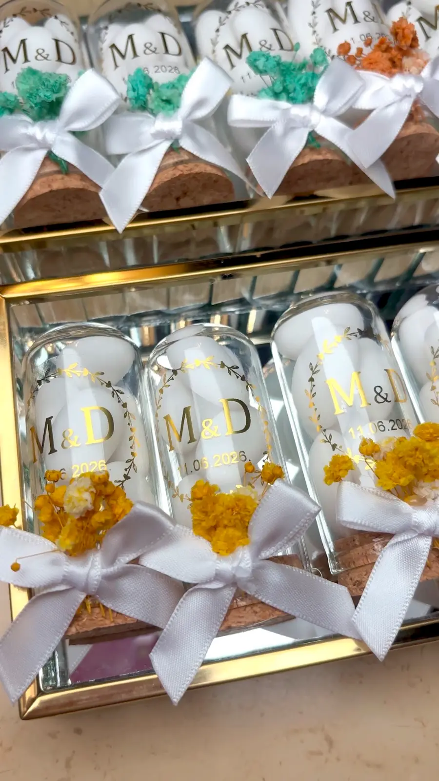 Glaskuppeln auf Korksockel mit goldenem Monogramm und Datum, in mehreren Farben